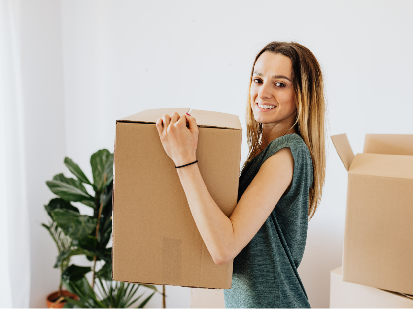 Woman carrying an open moving box during a home organizing and pre-move packing session with Next Chapter Solutions in Western New York.